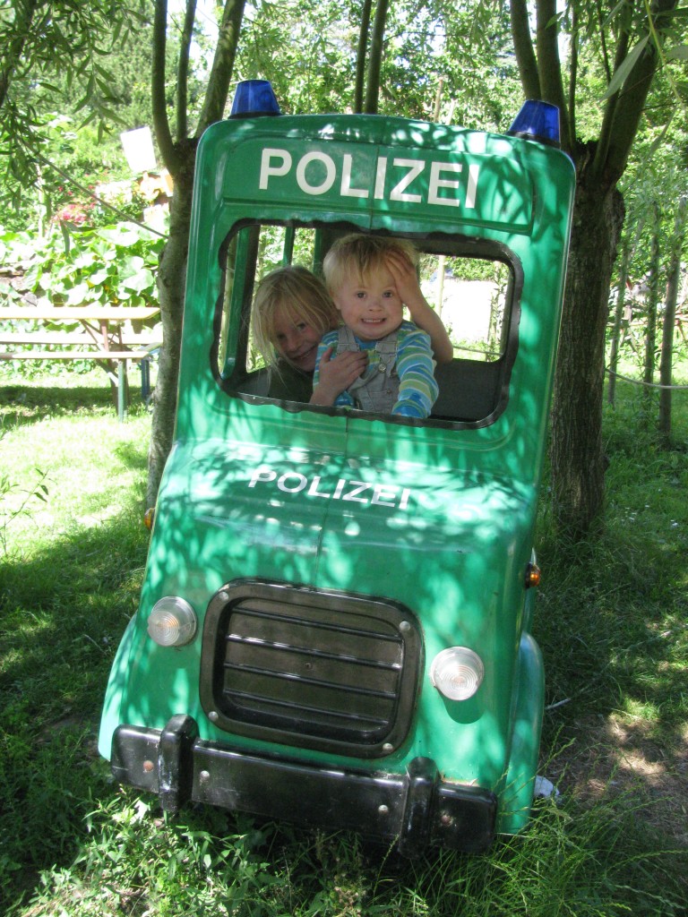 Zwei kleine Kinder in einem Polizei-Spielauto