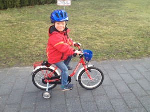Kind mit einem Fahrradhelm auf einem Kinderfahrrad mit Stützrädern