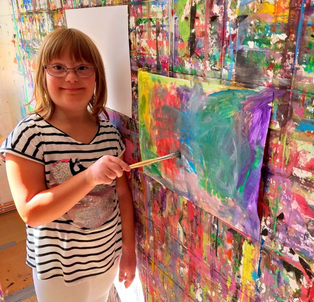 ein Mädchen malt mit einem Pinsel ein Bild