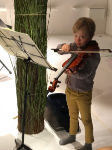 ein Junge steht mit einer Geige vor einem Notenständer