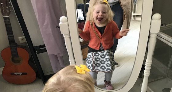ein lachendes kleines Mädchen vor einem Spiegel